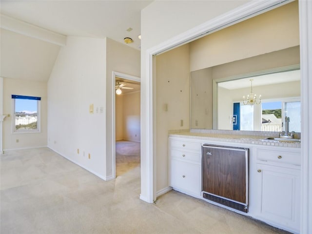 kitchen with a sink, lofted ceiling with beams, white cabinets, light countertops, and light colored carpet