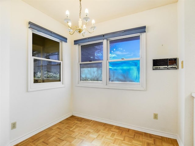 unfurnished room with baseboards and an inviting chandelier