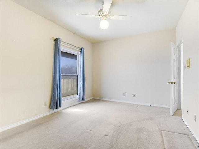 carpeted empty room featuring a ceiling fan and baseboards