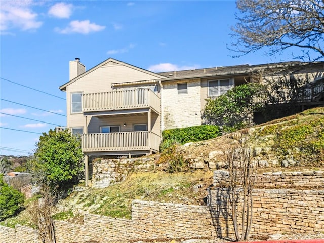 back of property with a balcony and a chimney