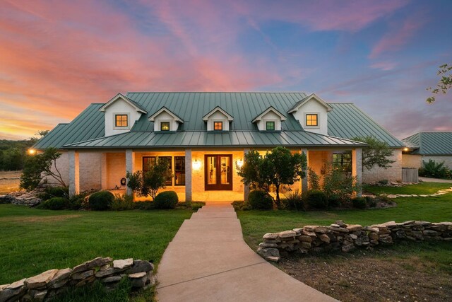 view of front of property featuring metal roof, covered porch, a front lawn, and a standing seam roof