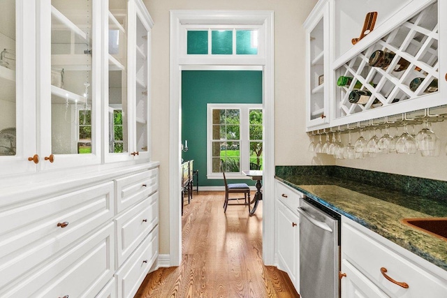 bar with a bar, dishwasher, and light wood-style flooring