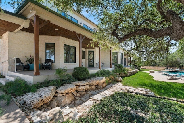 view of front of house featuring an outdoor pool, stucco siding, and a patio