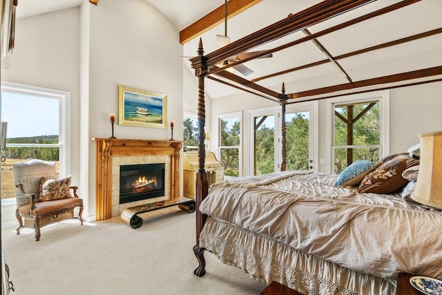 carpeted bedroom featuring a tiled fireplace, beam ceiling, and high vaulted ceiling