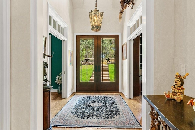 entrance foyer with french doors, baseboards, light wood-style floors, and a chandelier