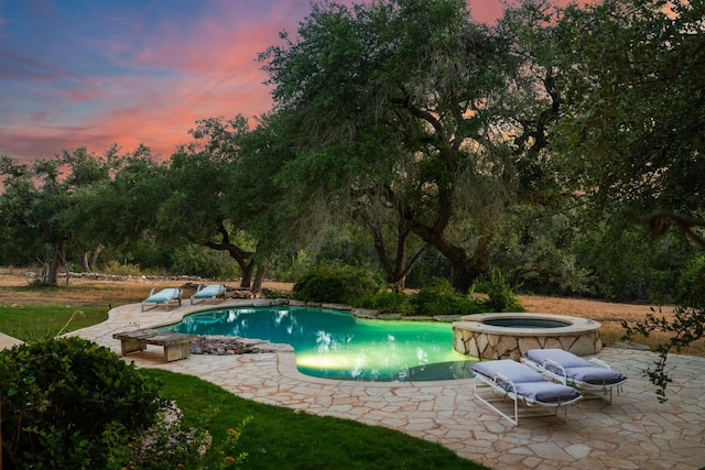 pool at dusk featuring a patio and a pool with connected hot tub