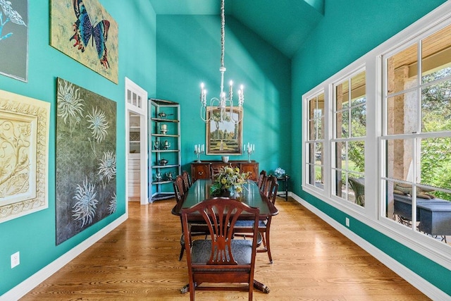 dining room featuring a notable chandelier, a healthy amount of sunlight, baseboards, and wood finished floors