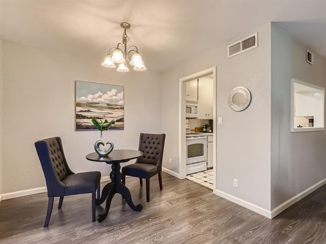 dining space featuring visible vents, baseboards, an inviting chandelier, and wood finished floors