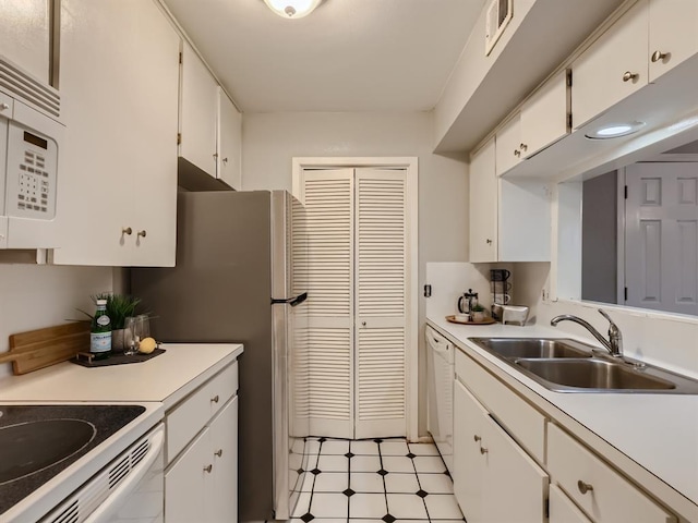 kitchen with a sink, white appliances, white cabinets, and light countertops