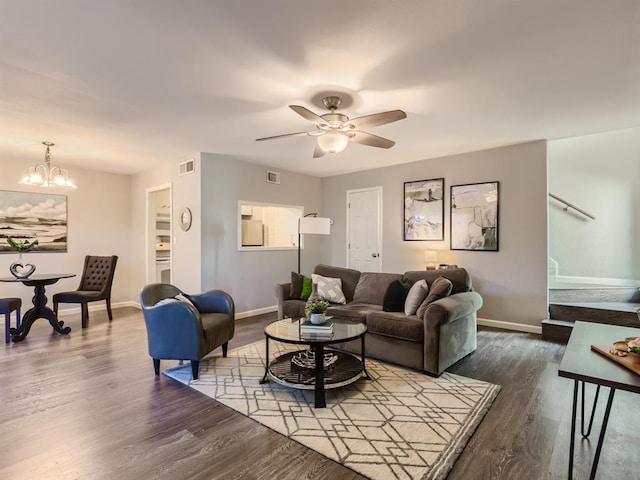 living room featuring stairway, ceiling fan with notable chandelier, dark wood-style flooring, and baseboards