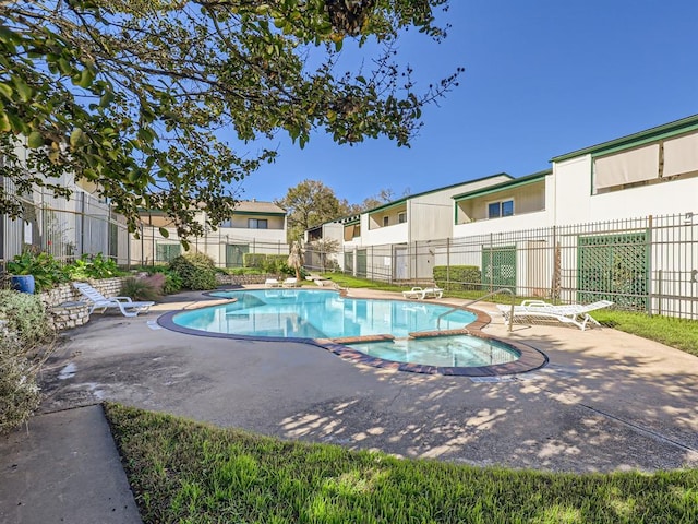 community pool featuring a patio area, a community hot tub, and fence