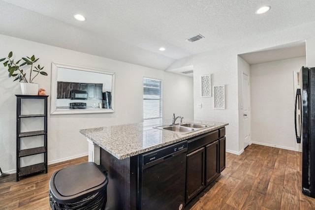 kitchen with visible vents, black appliances, a center island with sink, a sink, and dark wood-style flooring