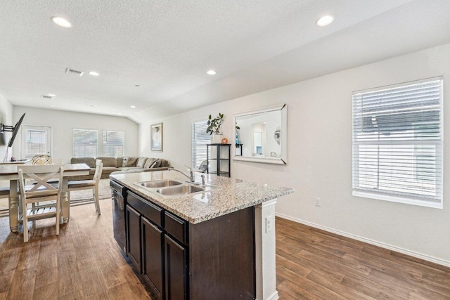 kitchen with visible vents, dark brown cabinets, dark wood finished floors, open floor plan, and a sink