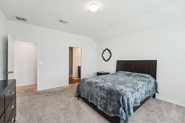 carpeted bedroom with visible vents and vaulted ceiling