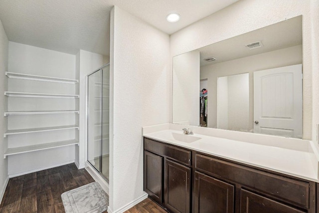 full bathroom featuring vanity, wood finished floors, visible vents, baseboards, and a shower stall