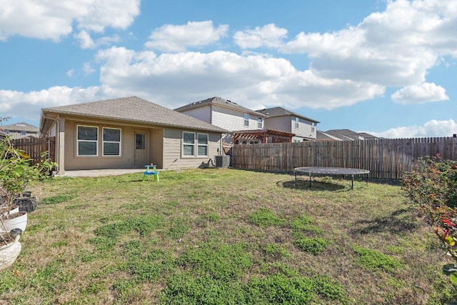 back of property with a trampoline, central air condition unit, a lawn, a fenced backyard, and a patio