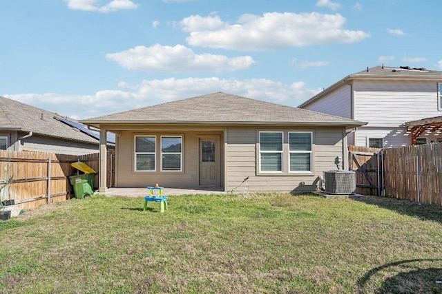 back of house featuring a lawn, a fenced backyard, and central AC