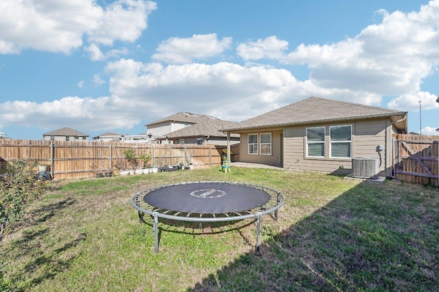 view of yard with a fenced backyard, central air condition unit, and a trampoline