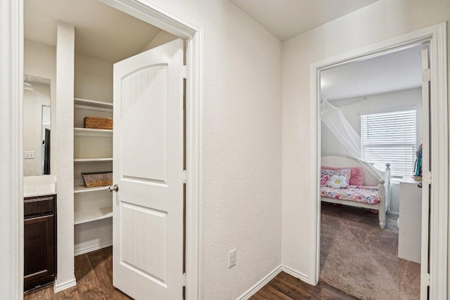 corridor with baseboards, dark wood-type flooring, and a textured wall