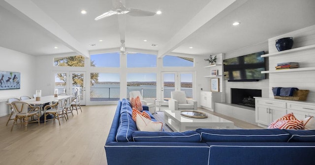 living room featuring light wood-type flooring, visible vents, a large fireplace, ceiling fan, and vaulted ceiling with beams