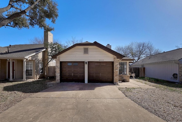 exterior space featuring concrete driveway, a chimney, an attached garage, and fence