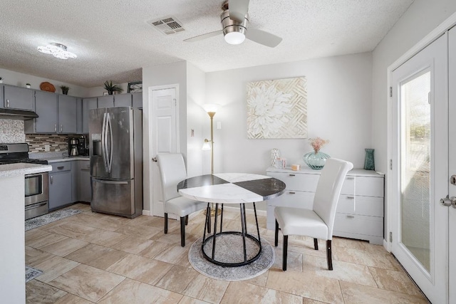 kitchen featuring visible vents, gray cabinetry, under cabinet range hood, light countertops, and appliances with stainless steel finishes