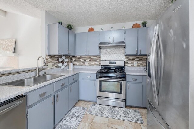 kitchen with a sink, appliances with stainless steel finishes, light countertops, and under cabinet range hood