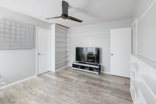 unfurnished living room with ceiling fan, wood finished floors, baseboards, and a textured ceiling