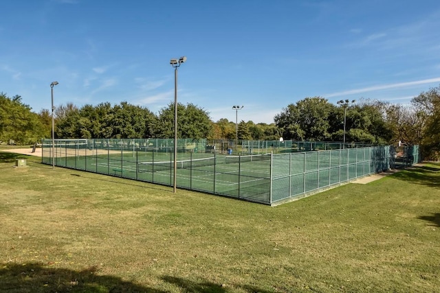 view of tennis court featuring a yard and fence