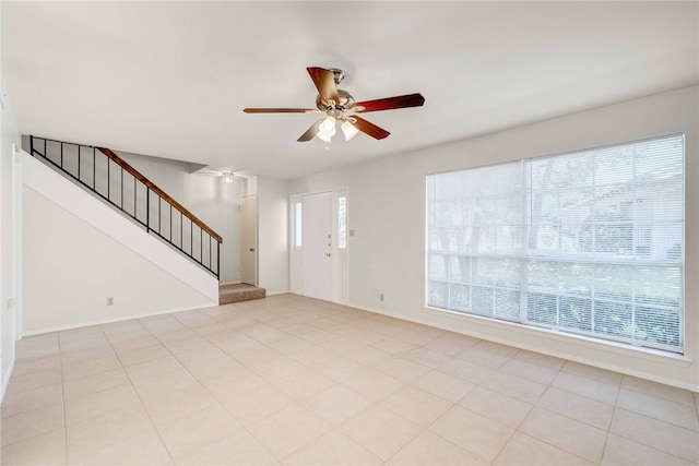 entryway with stairway, light tile patterned floors, a ceiling fan, and baseboards