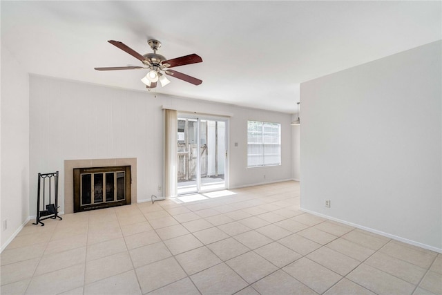 unfurnished living room with baseboards, a ceiling fan, a tiled fireplace, and tile patterned flooring