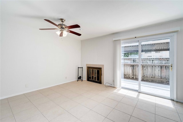 unfurnished living room with ceiling fan, light tile patterned floors, baseboards, and a tile fireplace