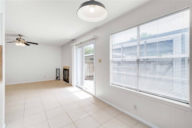 unfurnished living room featuring light tile patterned floors, baseboards, and ceiling fan