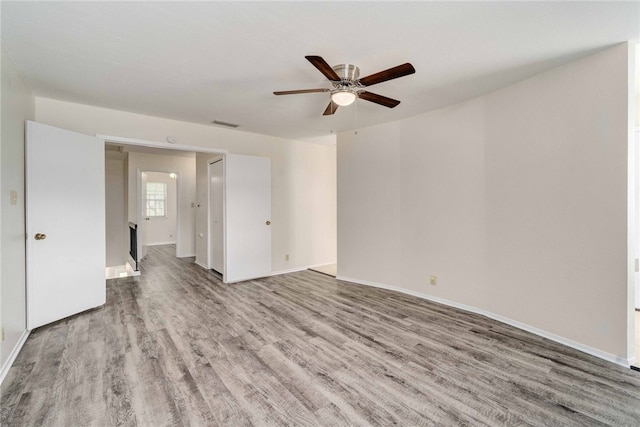 empty room with visible vents, baseboards, wood finished floors, and a ceiling fan