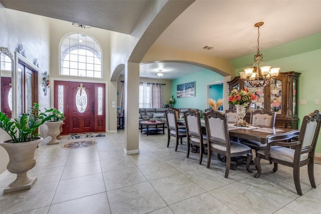 entrance foyer with light tile patterned floors, visible vents, baseboards, an inviting chandelier, and arched walkways