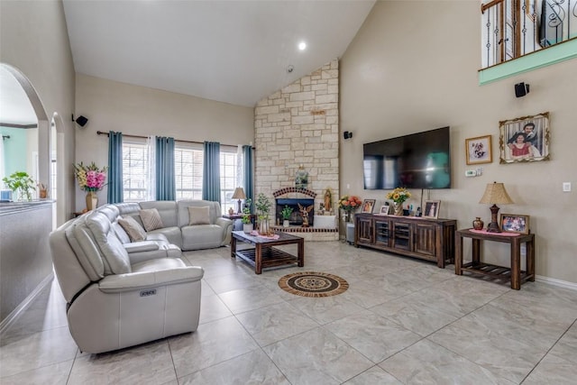 living area with arched walkways, a fireplace, and high vaulted ceiling