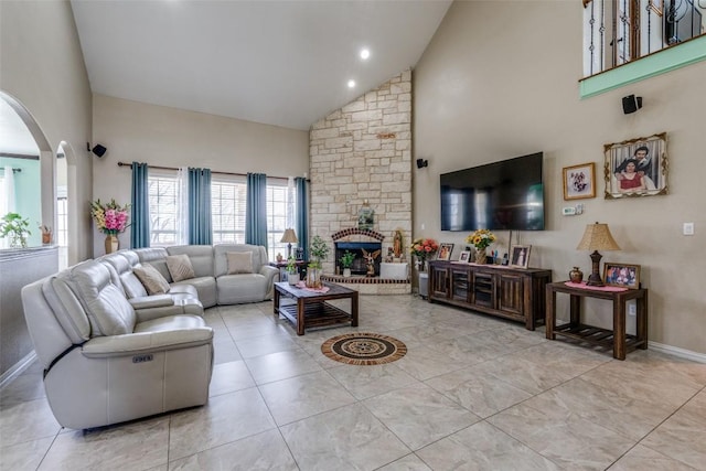 tiled living area with baseboards, a fireplace, arched walkways, and high vaulted ceiling