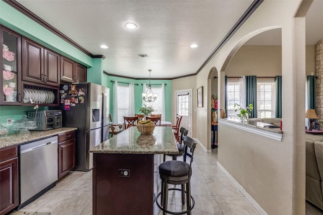 kitchen with light tile patterned floors, stainless steel appliances, a kitchen breakfast bar, and a healthy amount of sunlight