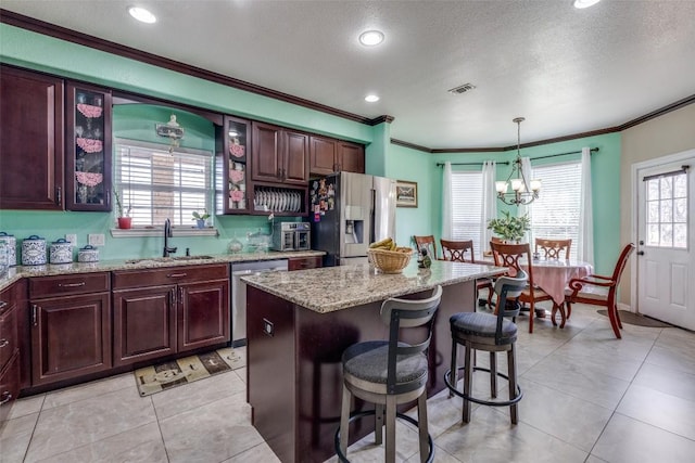 kitchen with visible vents, a breakfast bar, a sink, stainless steel appliances, and glass insert cabinets