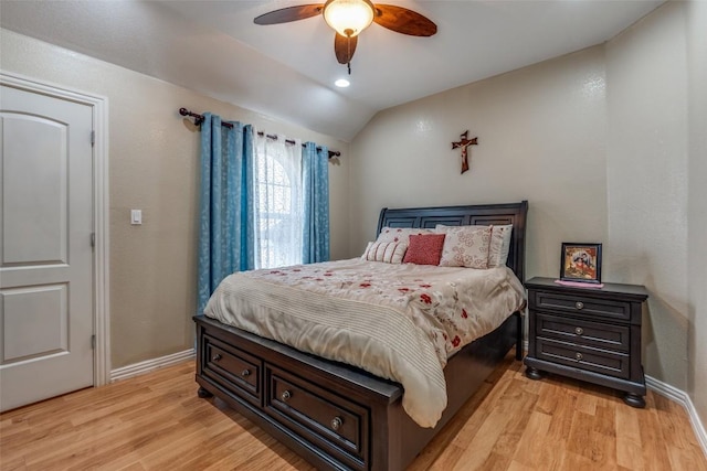 bedroom with baseboards, vaulted ceiling, and light wood finished floors