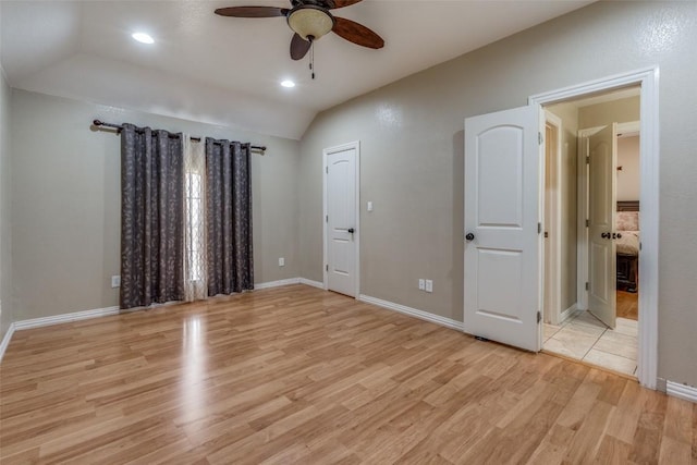 unfurnished bedroom featuring baseboards, lofted ceiling, and light wood-style floors