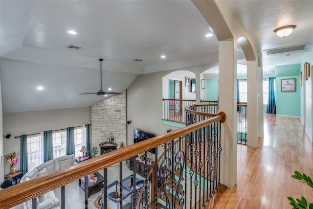 corridor featuring a wealth of natural light, visible vents, light wood-style floors, and lofted ceiling