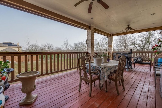 wooden terrace featuring outdoor dining area and a ceiling fan