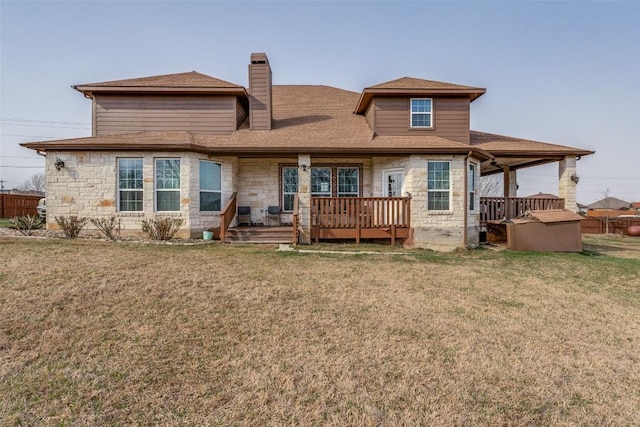 back of property with a yard, stone siding, and a chimney