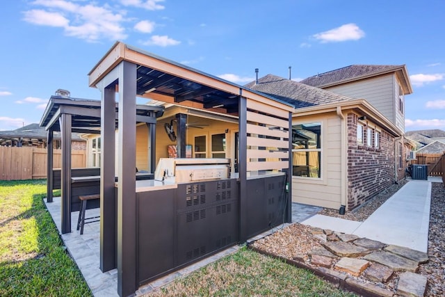 view of side of property featuring roof with shingles, a fenced backyard, central air condition unit, a patio area, and brick siding