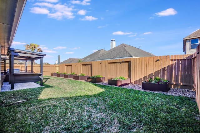 view of yard with a hot tub, a fenced backyard, and a garden