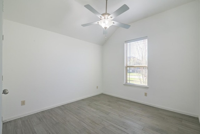 spare room featuring a ceiling fan, lofted ceiling, baseboards, and wood finished floors