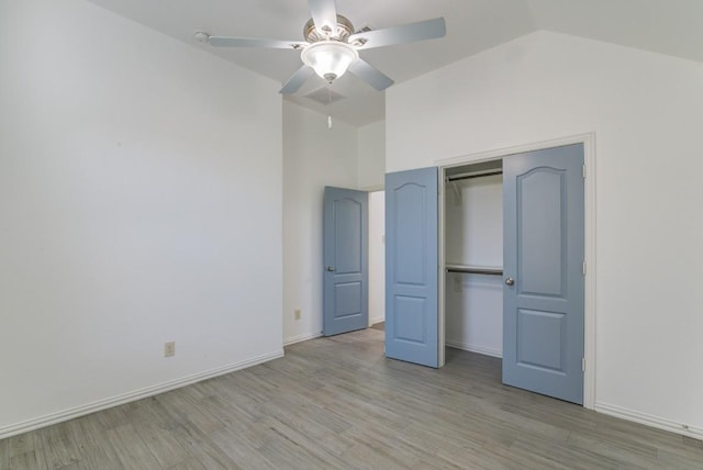 unfurnished bedroom featuring vaulted ceiling, baseboards, light wood-type flooring, and a closet