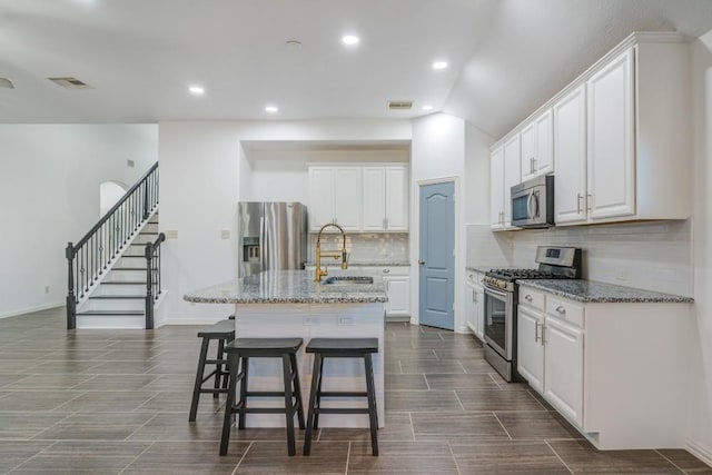 kitchen with a breakfast bar area, visible vents, white cabinets, and stainless steel appliances