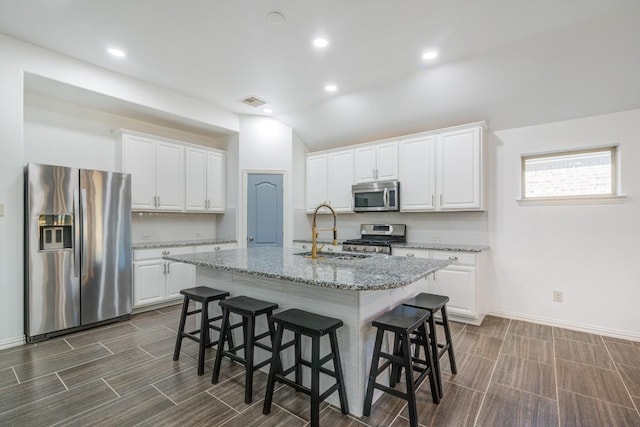 kitchen with a breakfast bar, a sink, tasteful backsplash, white cabinetry, and stainless steel appliances